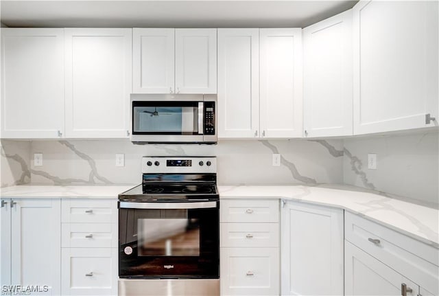 kitchen featuring light stone counters, backsplash, stainless steel appliances, and white cabinets