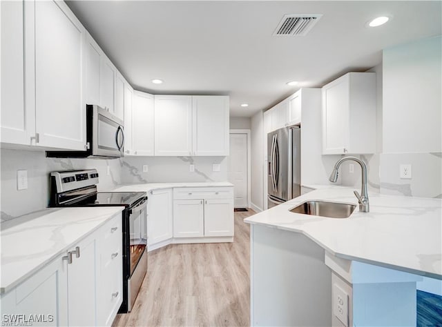 kitchen featuring sink, white cabinetry, light hardwood / wood-style flooring, appliances with stainless steel finishes, and kitchen peninsula