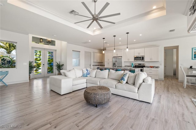 living room with french doors, crown molding, light hardwood / wood-style flooring, a tray ceiling, and ceiling fan