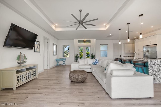 living room featuring french doors, a raised ceiling, sink, and light hardwood / wood-style flooring