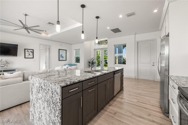 kitchen with sink, white cabinetry, a raised ceiling, stainless steel appliances, and a kitchen island with sink