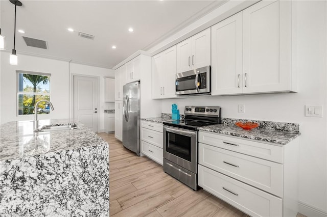 kitchen featuring sink, hanging light fixtures, white cabinets, and appliances with stainless steel finishes