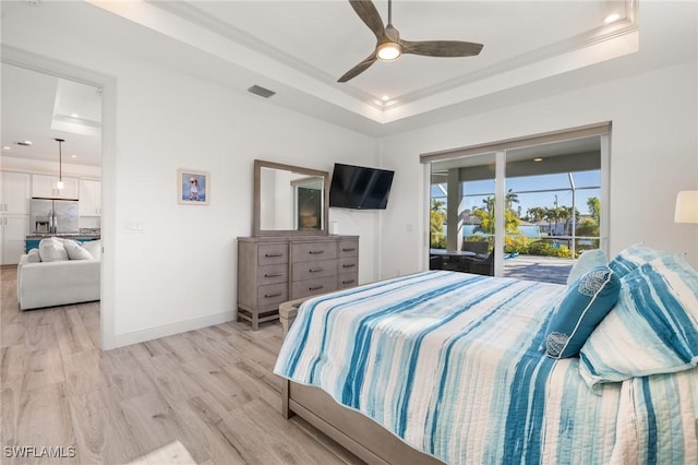 bedroom featuring ceiling fan, access to exterior, a tray ceiling, stainless steel fridge with ice dispenser, and light wood-type flooring