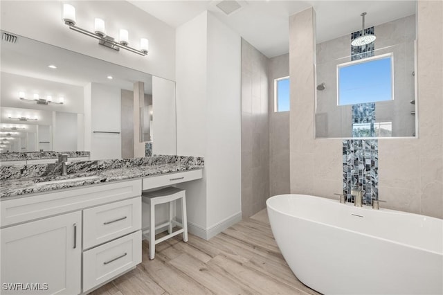 bathroom with vanity, a bathtub, hardwood / wood-style floors, and tile walls