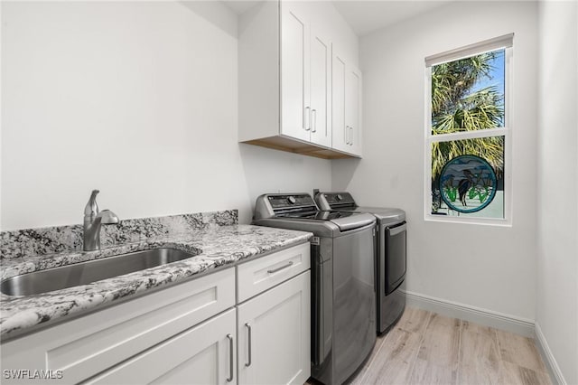 washroom featuring cabinets, washer and dryer, sink, and light wood-type flooring