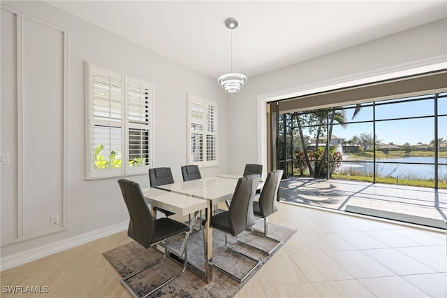 dining area with light tile patterned floors, a chandelier, and a water view