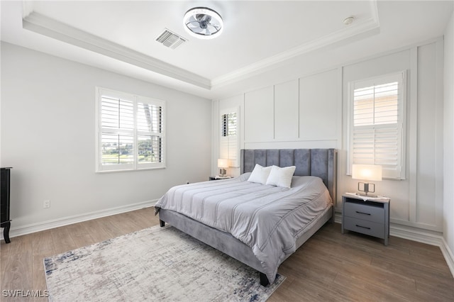 bedroom with a raised ceiling, crown molding, and hardwood / wood-style floors