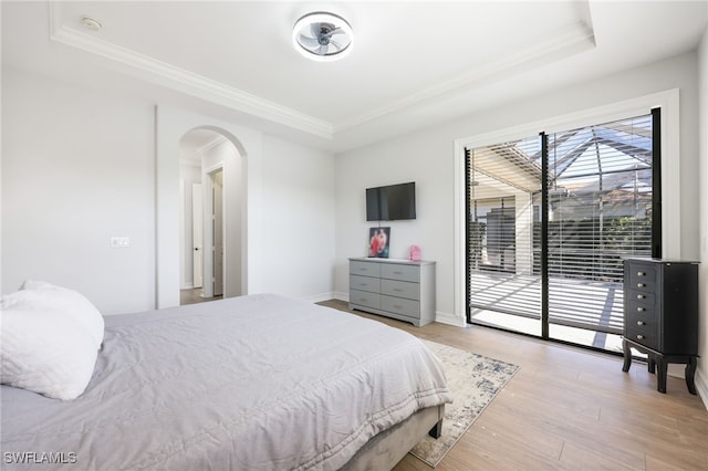 bedroom featuring crown molding, access to outside, light hardwood / wood-style floors, and a raised ceiling