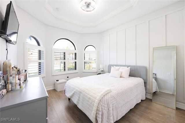 bedroom with a raised ceiling, ornamental molding, and dark hardwood / wood-style flooring