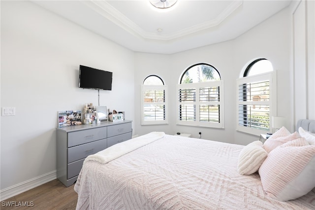 bedroom featuring hardwood / wood-style flooring, a tray ceiling, and crown molding