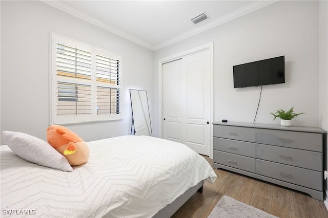 bedroom with crown molding, dark hardwood / wood-style flooring, and a closet