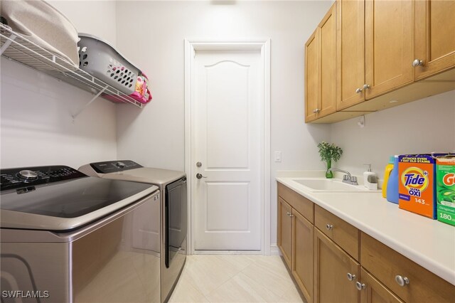 laundry room with cabinets, washing machine and clothes dryer, and sink