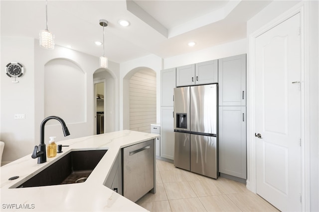 kitchen with sink, appliances with stainless steel finishes, gray cabinetry, light stone countertops, and decorative light fixtures