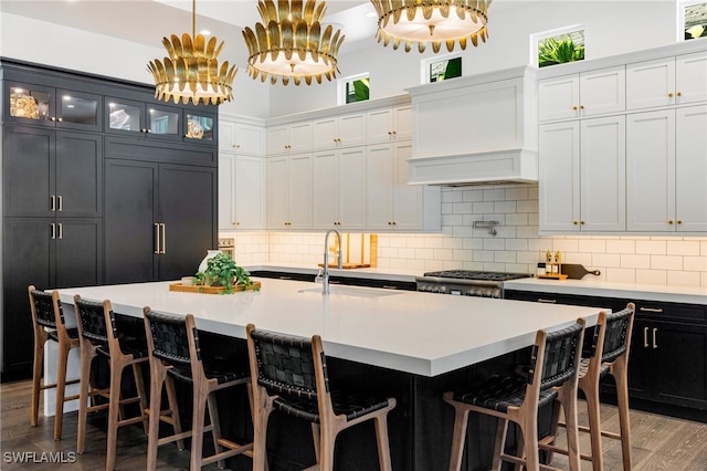 kitchen featuring sink, decorative light fixtures, light wood-type flooring, an island with sink, and stove