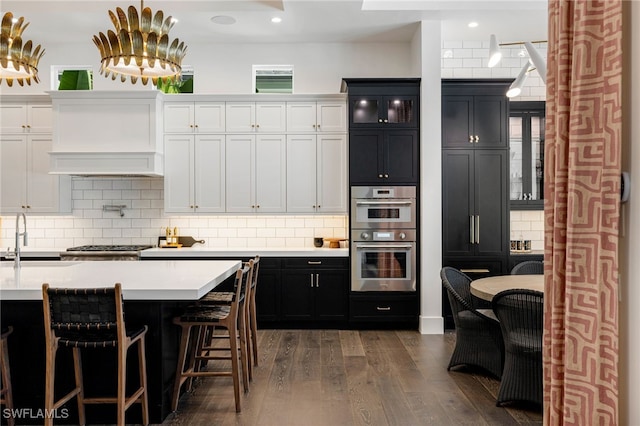 kitchen with premium range hood, white cabinetry, backsplash, dark hardwood / wood-style floors, and stainless steel double oven