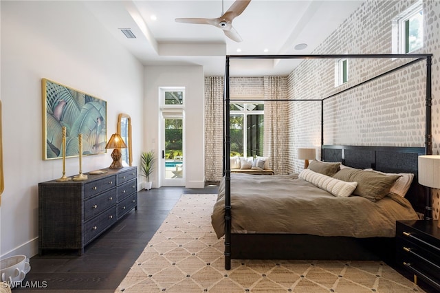 bedroom with access to exterior, dark wood-type flooring, ceiling fan, and brick wall