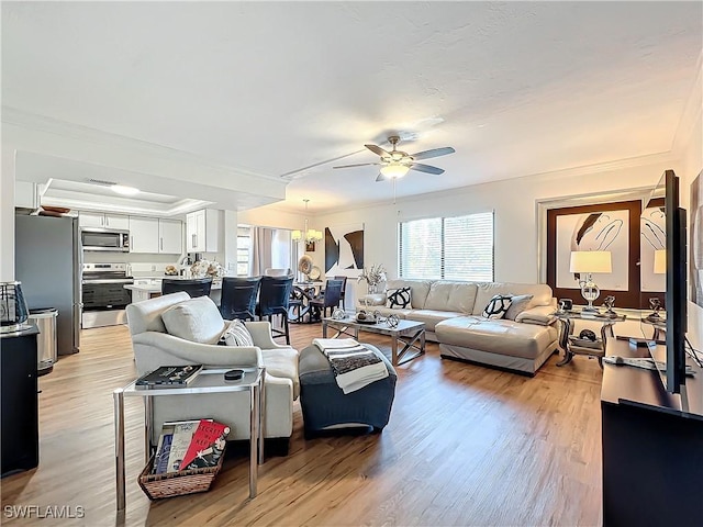 living room with ceiling fan, ornamental molding, and light hardwood / wood-style flooring