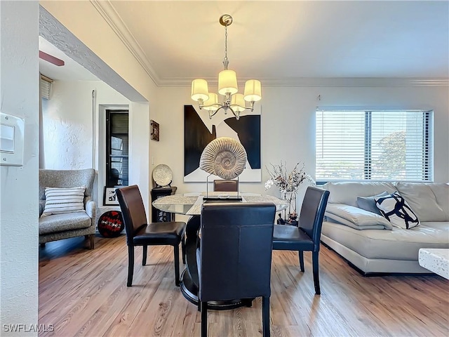 dining space with hardwood / wood-style flooring, crown molding, and an inviting chandelier