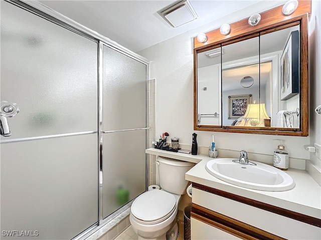 bathroom featuring a shower with door, vanity, and toilet