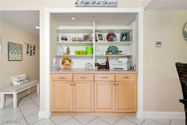 bar with light tile patterned flooring and light brown cabinetry