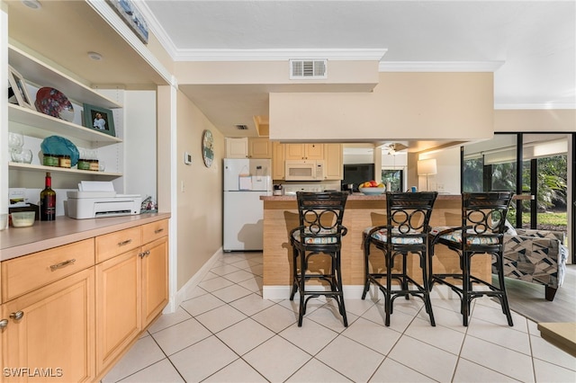 kitchen featuring light brown cabinetry, a breakfast bar, light tile patterned floors, ornamental molding, and white appliances