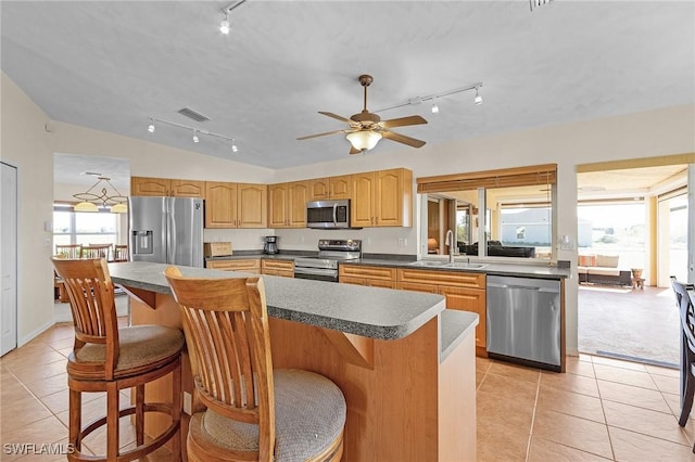 kitchen featuring vaulted ceiling, sink, a center island, light tile patterned floors, and stainless steel appliances