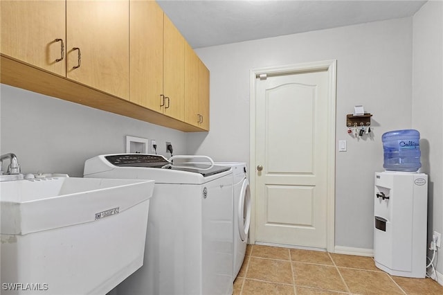 laundry area with sink, light tile patterned floors, washer and clothes dryer, and cabinets