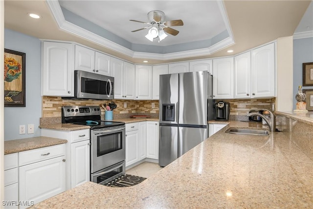 kitchen with white cabinetry, stainless steel appliances, and a raised ceiling