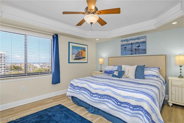 bedroom featuring hardwood / wood-style flooring, ornamental molding, a raised ceiling, and ceiling fan