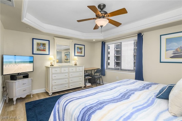 bedroom featuring crown molding, ceiling fan, a raised ceiling, and light wood-type flooring