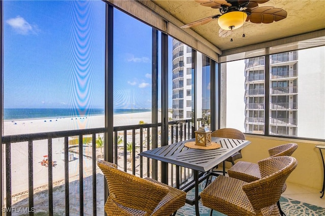 sunroom featuring a water view, a beach view, and ceiling fan