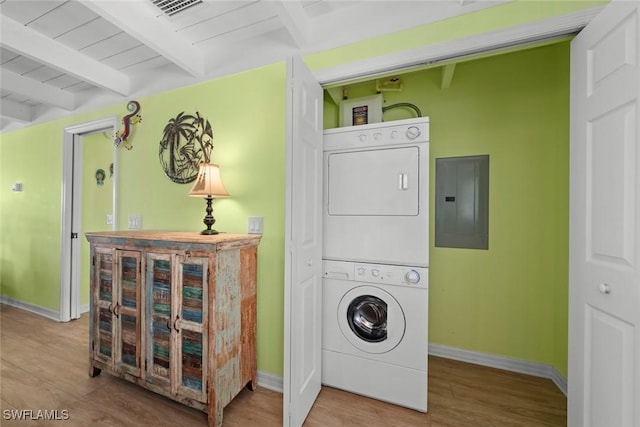 washroom featuring stacked washer / dryer, hardwood / wood-style flooring, and electric panel