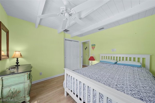 bedroom with vaulted ceiling with beams, light hardwood / wood-style flooring, wooden ceiling, and a closet