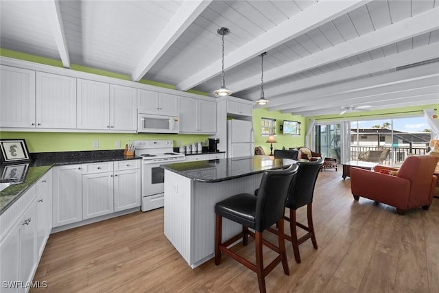 kitchen with white appliances, decorative light fixtures, a center island, and white cabinets