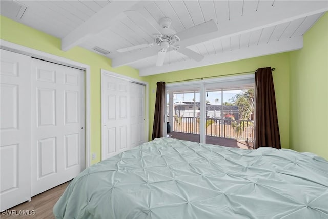 bedroom with beamed ceiling, wood ceiling, two closets, and access to outside