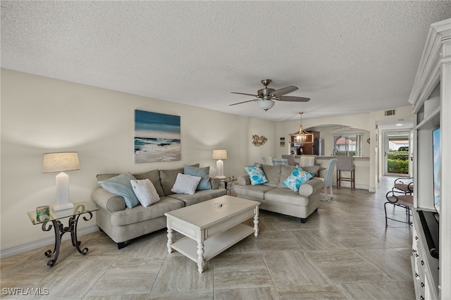 living room featuring ceiling fan and a textured ceiling