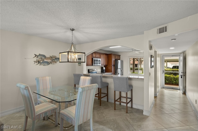 tiled dining room with ceiling fan with notable chandelier