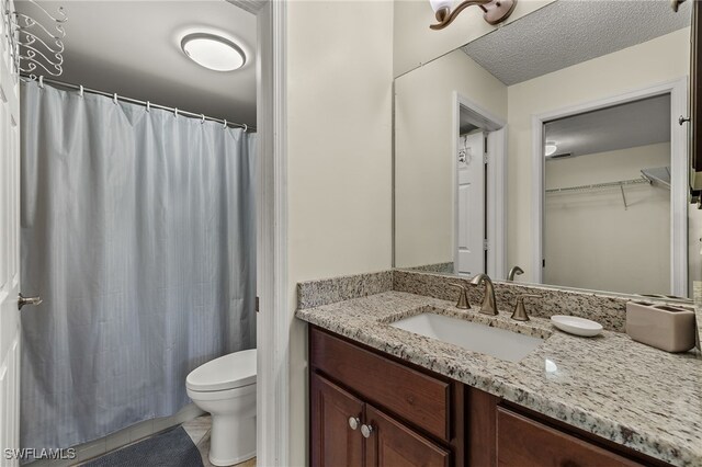 bathroom featuring vanity, toilet, curtained shower, and a textured ceiling