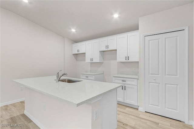 kitchen featuring sink, light hardwood / wood-style floors, white cabinets, and a center island with sink