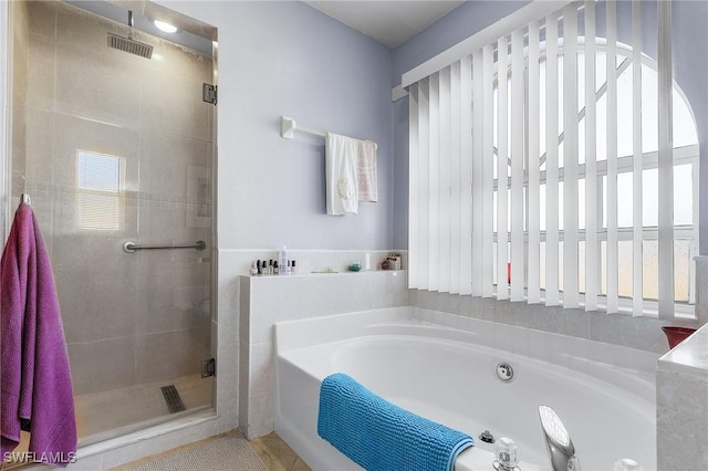 bathroom featuring plenty of natural light and separate shower and tub