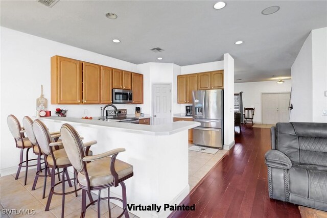 13380 Hampton Park Ct, Fort Myers, FL 33913 - kitchen with stainless steel appliances, a peninsula, light countertops, a kitchen bar, and recessed lighting