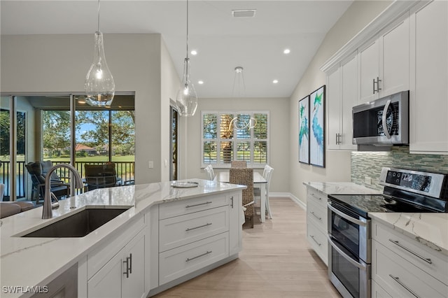 kitchen with light stone counters, stainless steel appliances, sink, and white cabinets