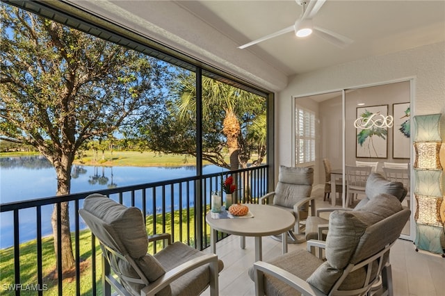 sunroom / solarium with a wealth of natural light, ceiling fan, and a water view