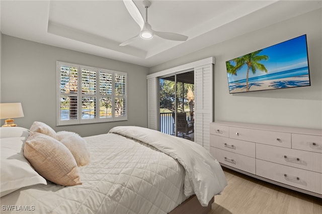 bedroom with a raised ceiling, ceiling fan, access to exterior, and light wood-type flooring