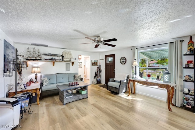 living room with a textured ceiling, light hardwood / wood-style floors, and ceiling fan