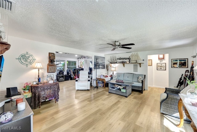 living room featuring ceiling fan, light hardwood / wood-style floors, and a textured ceiling