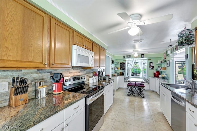 kitchen featuring sink, white cabinets, decorative backsplash, dark stone counters, and stainless steel appliances