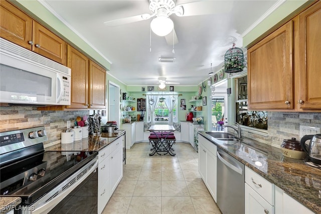 kitchen with white cabinetry, sink, dark stone countertops, light tile patterned floors, and stainless steel appliances