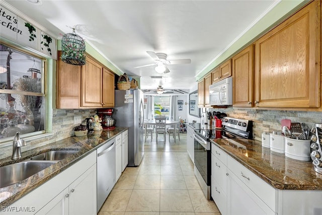 kitchen with light tile patterned flooring, sink, tasteful backsplash, dark stone countertops, and appliances with stainless steel finishes