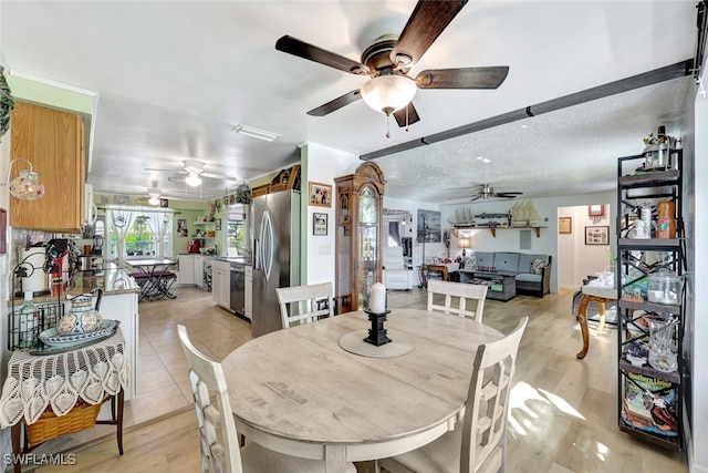 dining space with ceiling fan, a textured ceiling, and light wood-type flooring